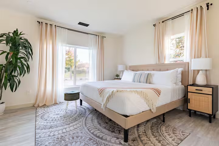 Spanish-style bedroom interior with arched window and linen sheets