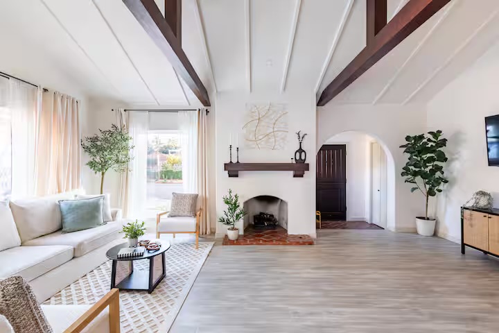 Vaulted living room with exposed beams, fireplace, and Spanish arched doorway